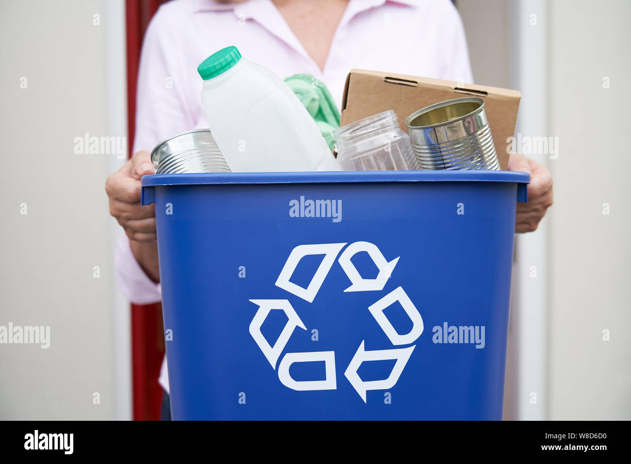 Close Up Of Woman Holding Recycling Bin Of Reusable Waste Outside Front Door Stock Photo
