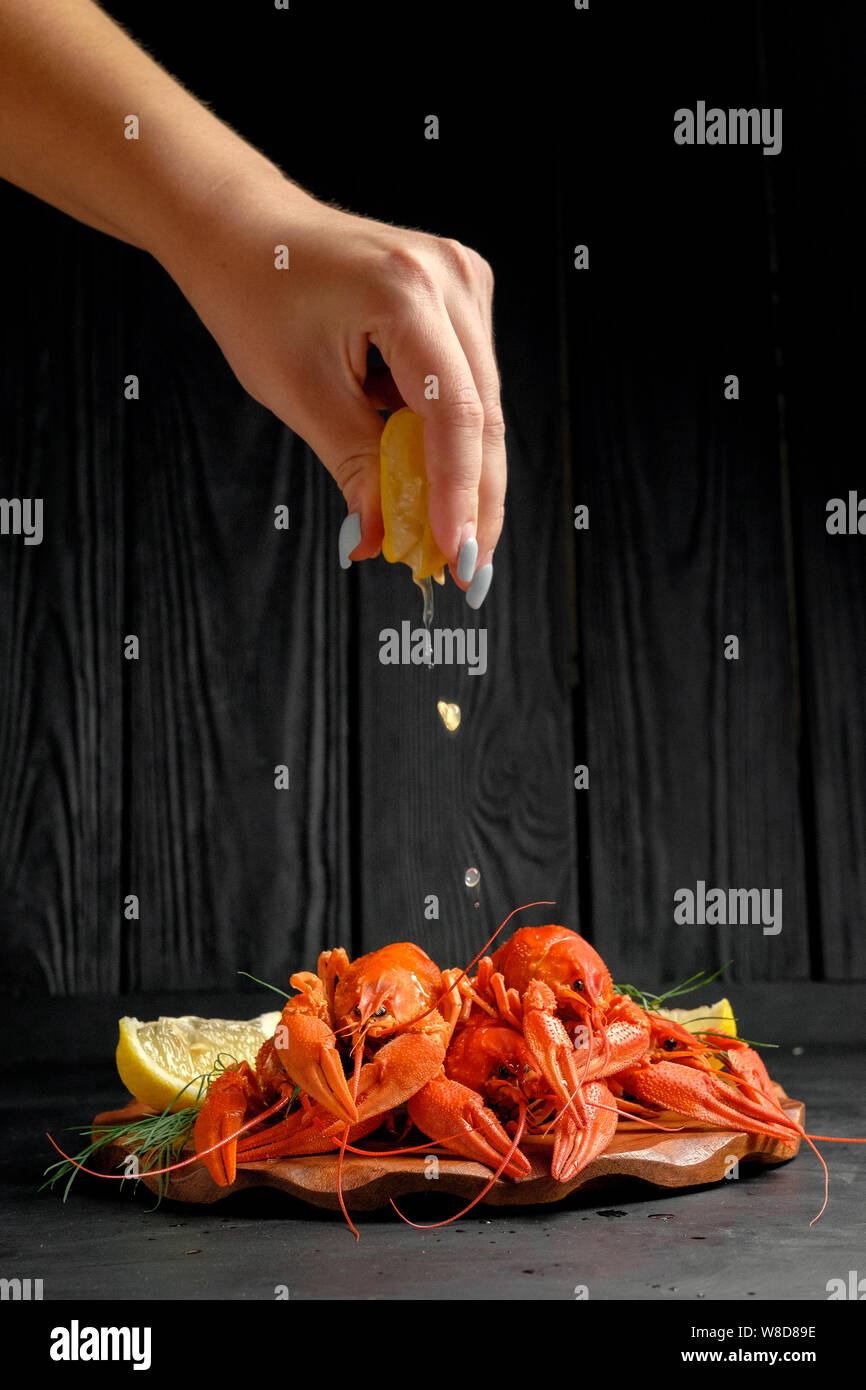 lobster with lemon lime and green dill on black background, hand of