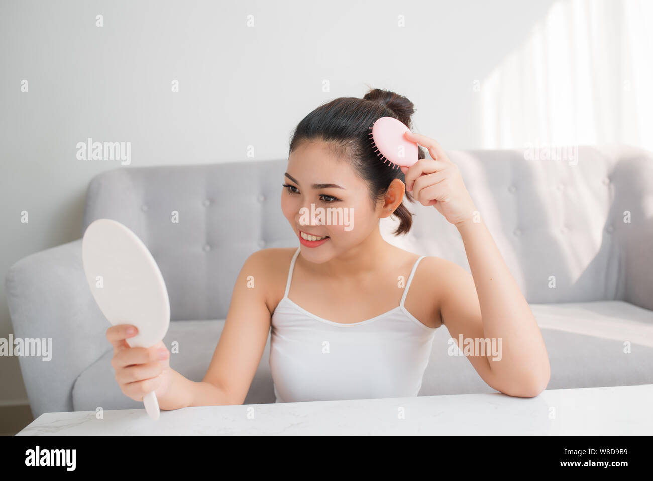 Young Asian woman combing hair and looking in mirror Stock Photo