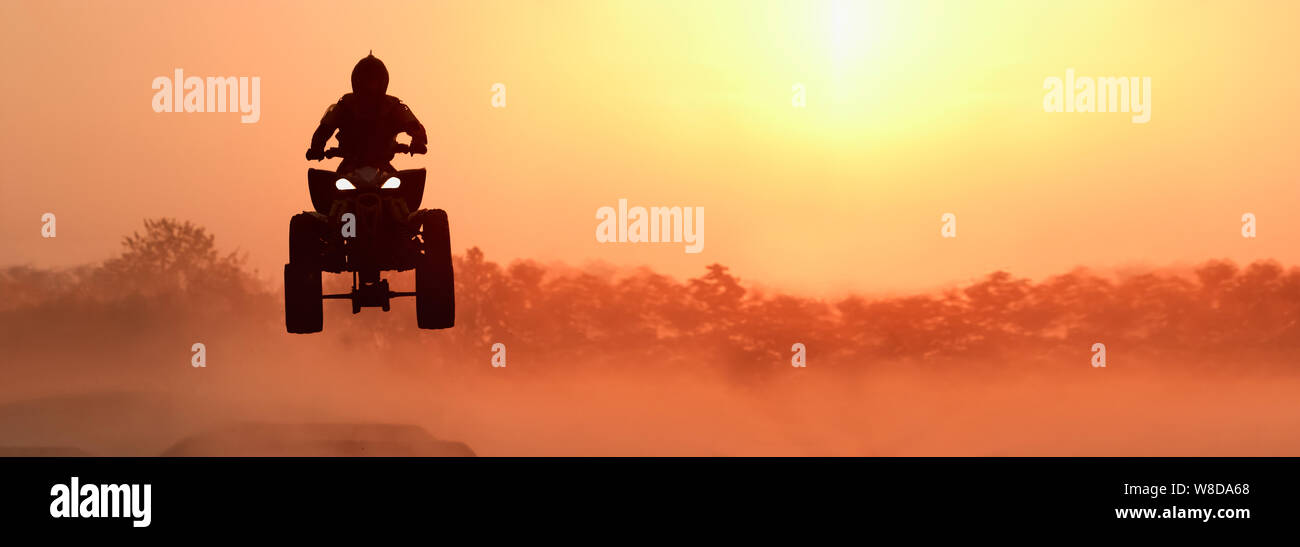 Silhouette ATV or Quad bikes Jump in sunset. Stock Photo