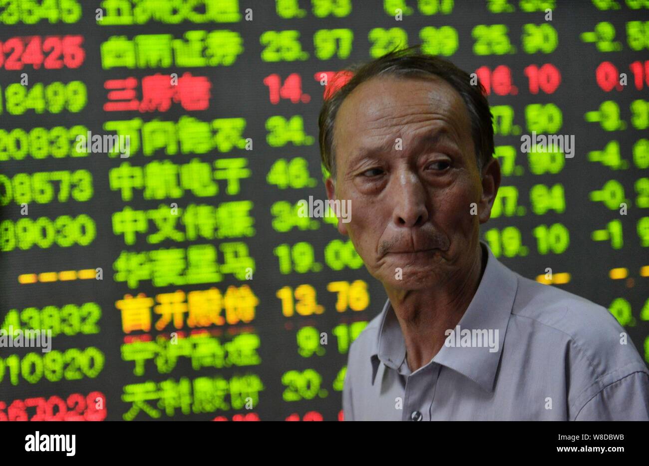 A Chinese investor looks worried in front of a screen displaying prices of  shares (red for price rising and green for price falling) at a stock broker  Stock Photo - Alamy