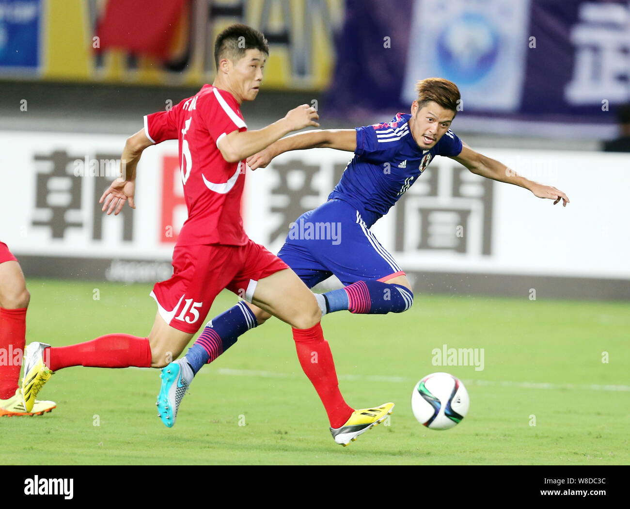 Hotaru Yamaguchi of Japan, right, challenges Ri Yong-chol of North Korea during their soccer match of the Men's East Asian Cup 2015 in Wuhan city, cen Stock Photo