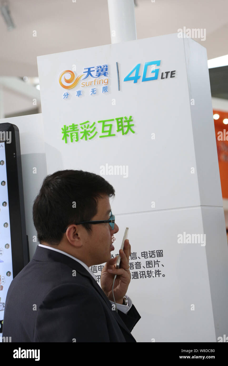 --FILE--A visitor tries out a smartphone at the stand of Tianyi Surfing 4G LTE of China Telecom during the 16th China International Industry Fair (CII Stock Photo