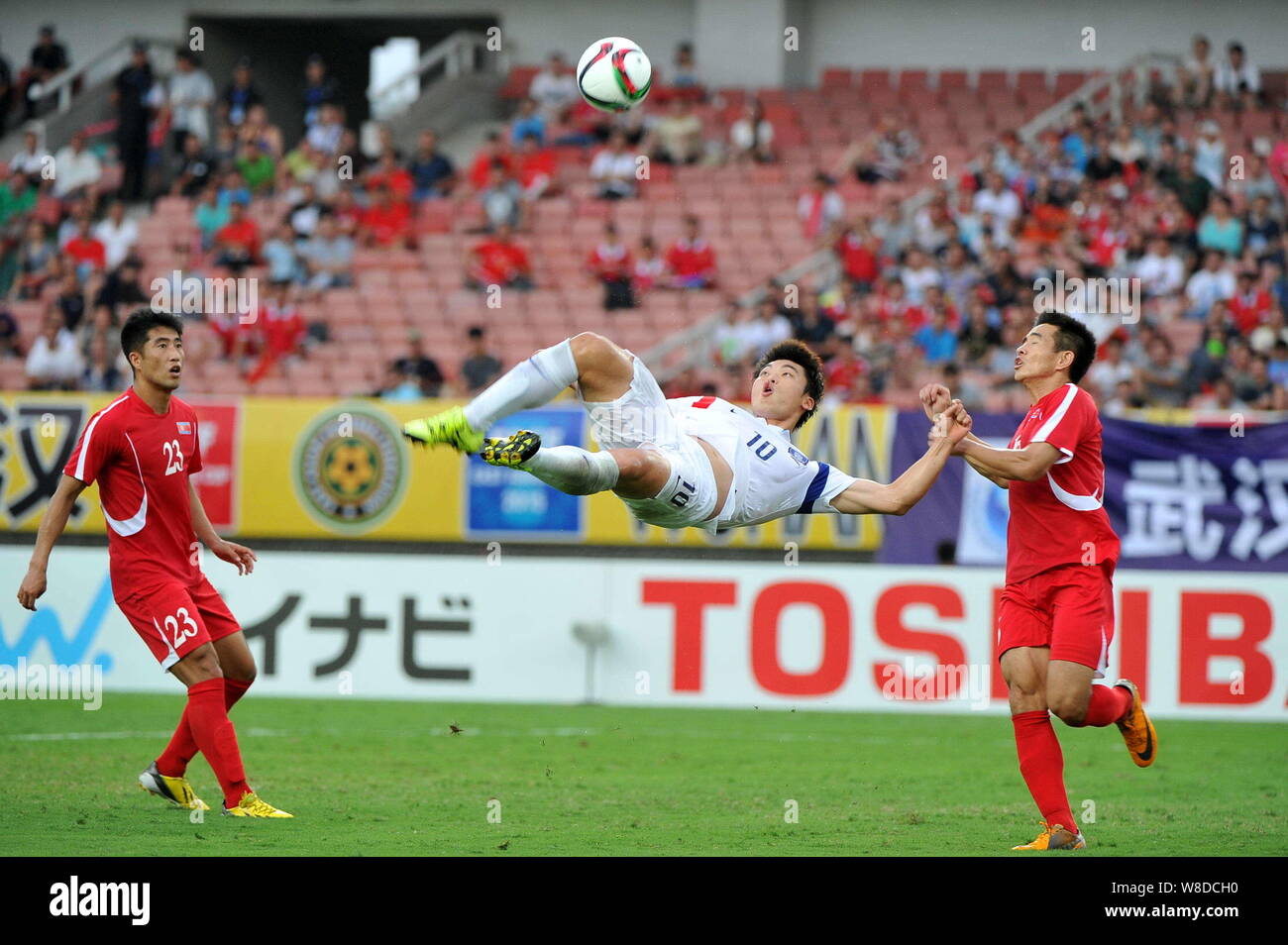 Ro Hak-su of North Korea, right, challenges Lee Jong-ho of South Korea, center, during their soccer match of the Men's East Asian Cup 2015 in Wuhan ci Stock Photo