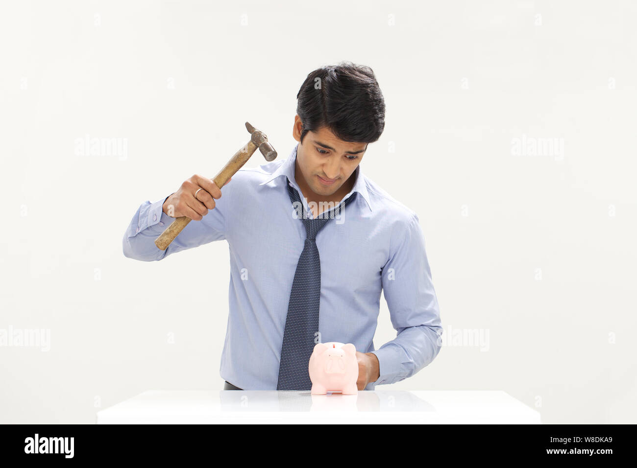 Businessman using hammer to smash a piggybank Stock Photo - Alamy