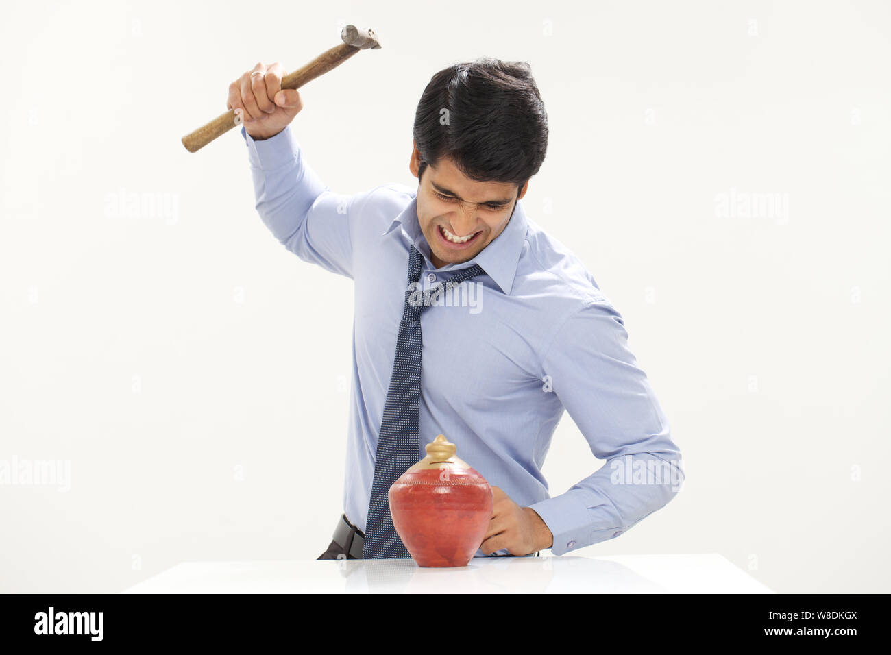 Businessman using hammer to smash a piggybank Stock Photo - Alamy