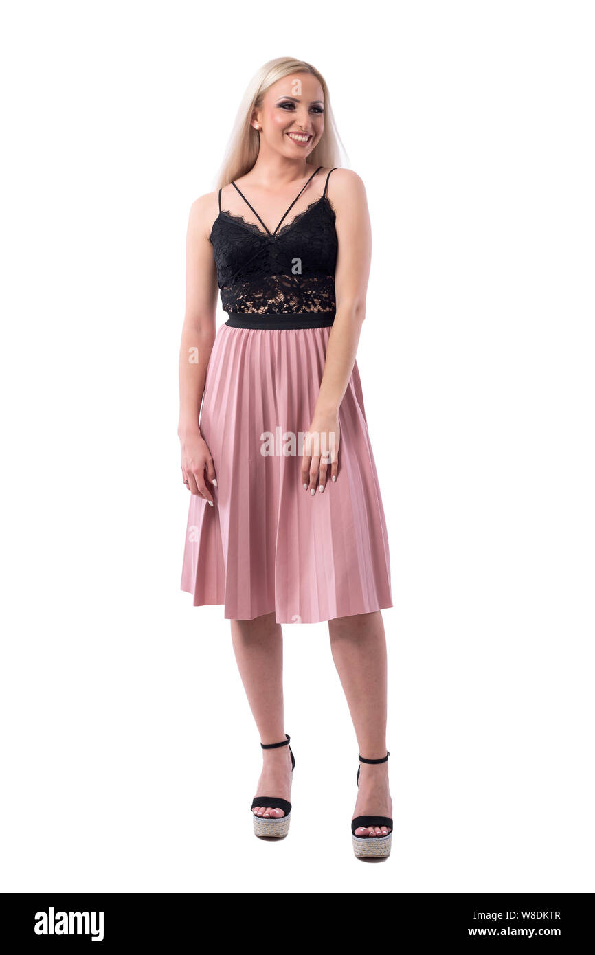 Cheerful young blonde woman in salmon color pleated skirt and lace top looking away. Full body isolated on white background. Stock Photo