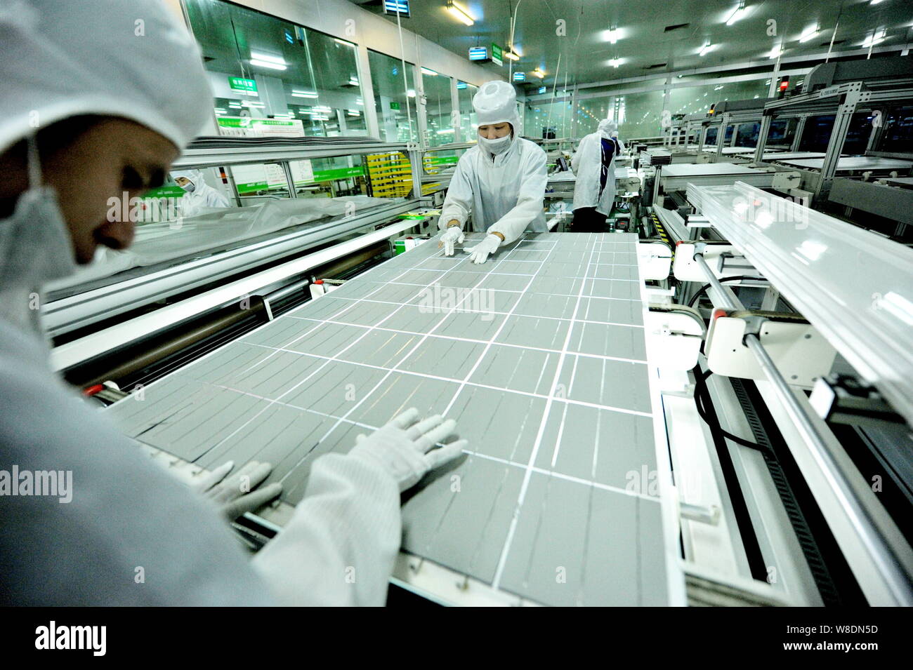 --FILE--Chinese workers line up photovoltaic cells to make a solar panel at the plant of Jinko Solar in Shangrao city, east China's Jiangxi province, Stock Photo