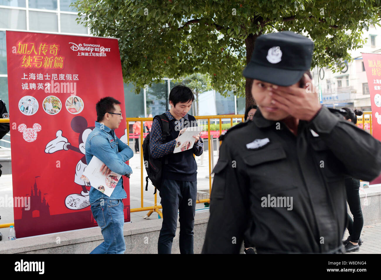 A Security Guard Rubs His Eye In Front Of Job Seekers Reading Pamphlets During A Recruitment Event For The Shanghai Disney Resort At Shanghai Talent T Stock Photo Alamy