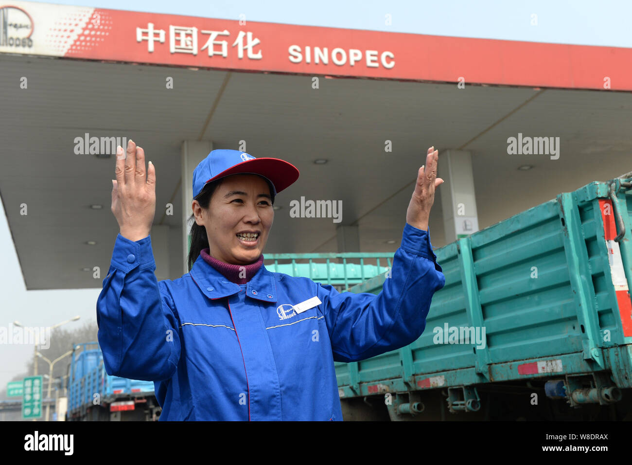 --FILE--A Chinese employee directs a truck to enter a gas station of Sinopec in Beijing, China, 25 March 2015.   China's top oil refiner Sinopec Corp Stock Photo