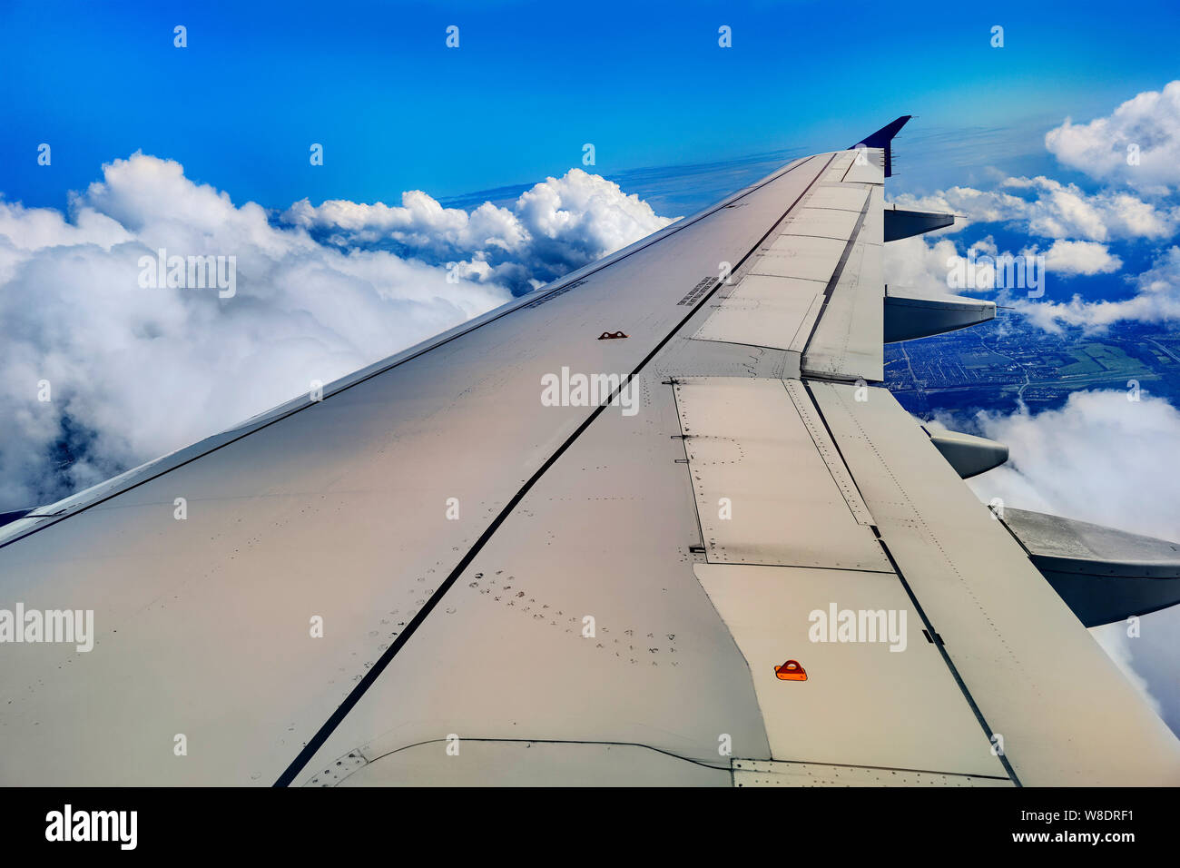 Plane wing above the clouds. A plane wing above the clouds at noon seen through a window of an aircraft, color toned travel concept picture Stock Photo