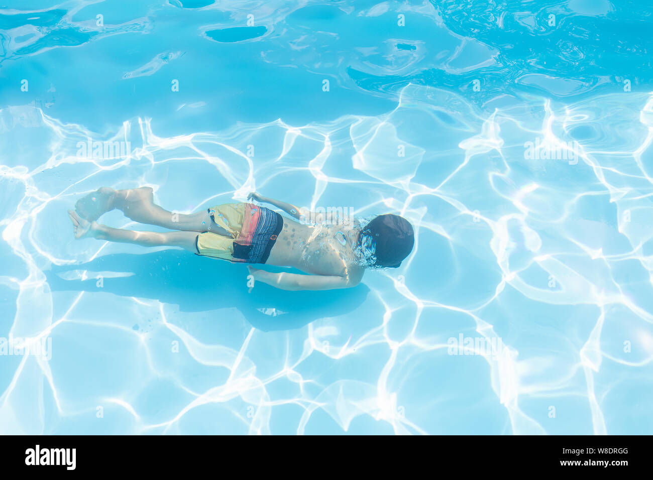 Kid diving in a swimming pool in summer Stock Photo