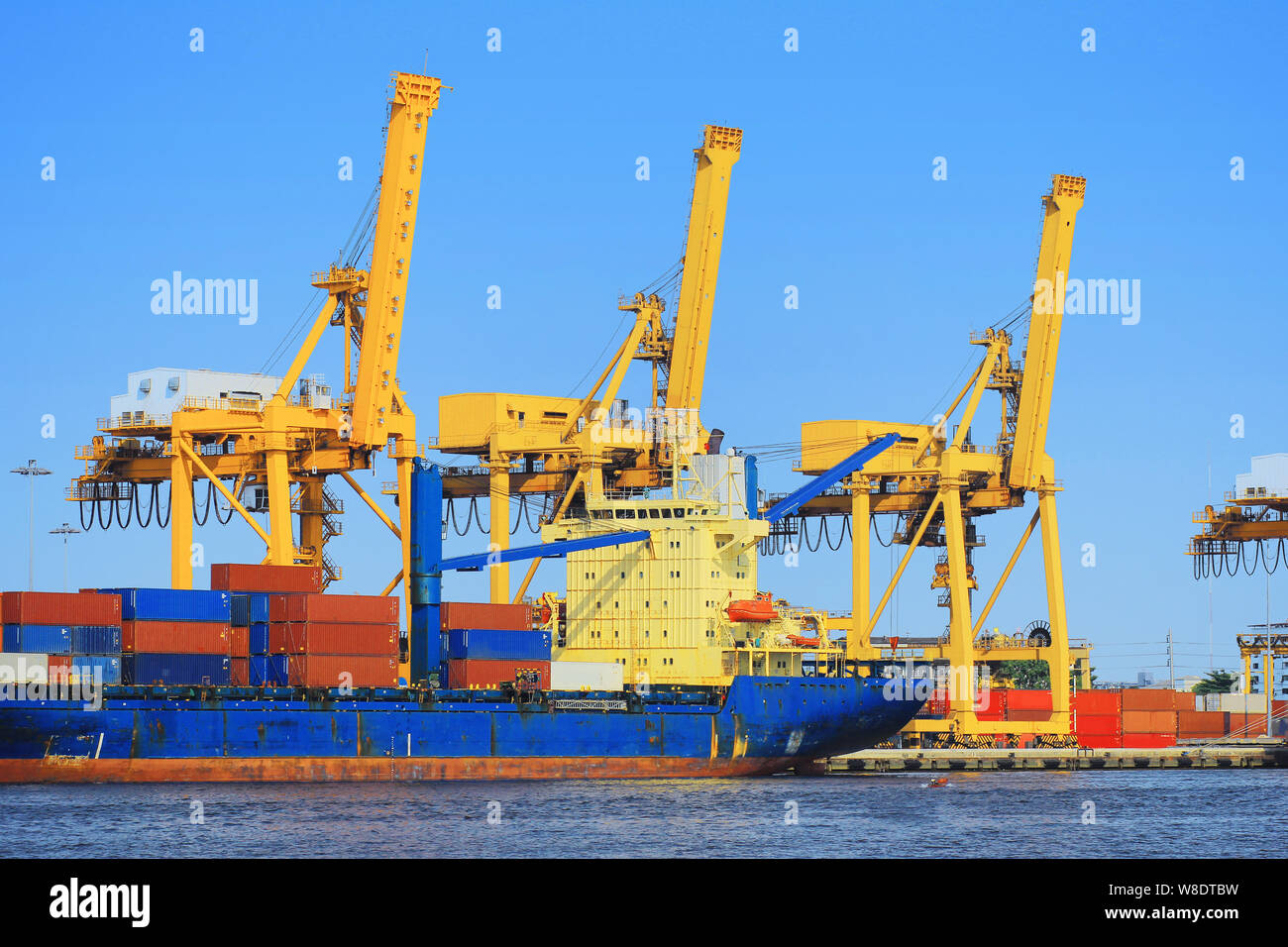 Container Cargo freight ship with working crane bridge in shipyard ...