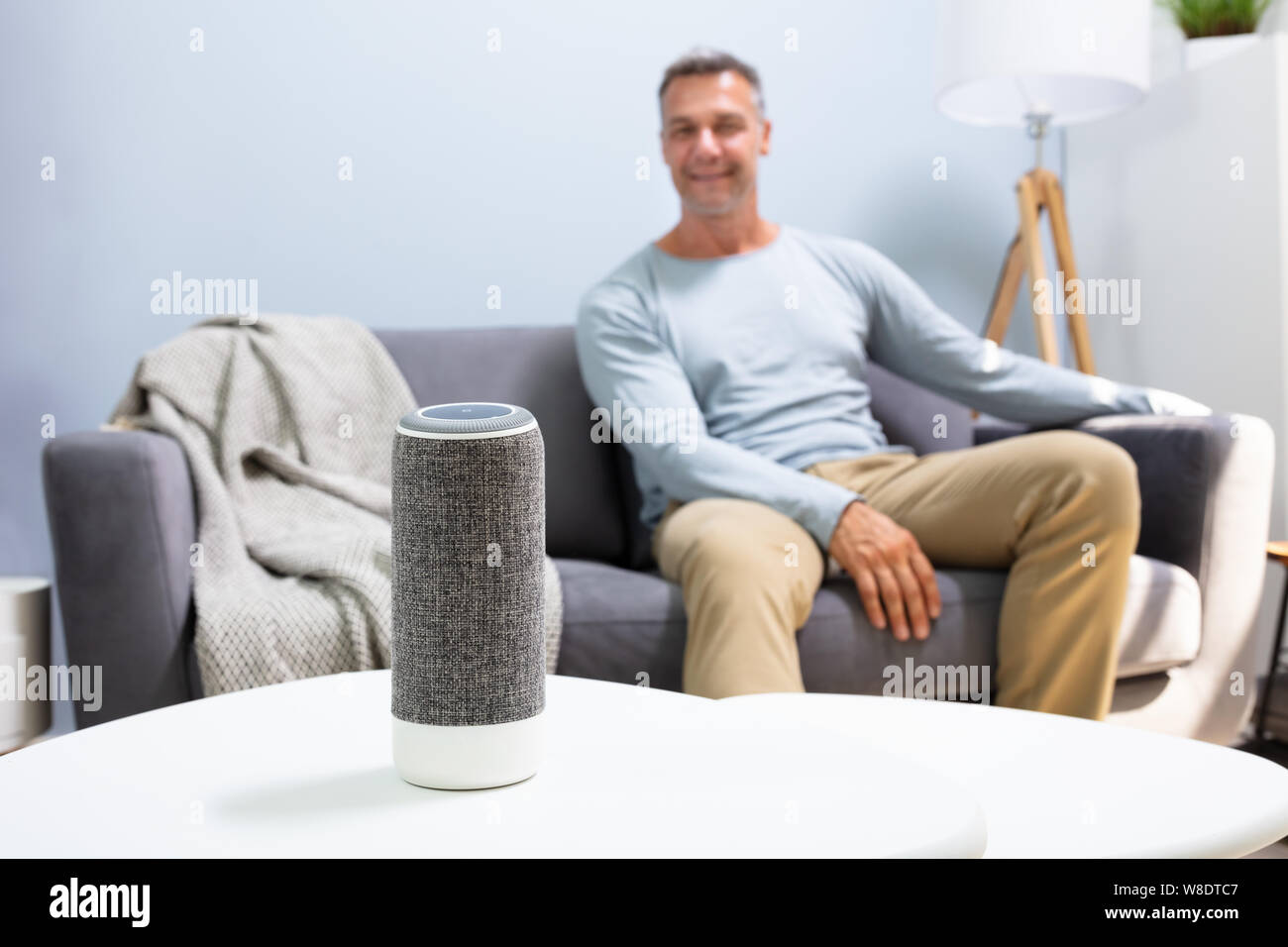Close-up Of Wireless Speaker In Front Of Man Sitting On Sofa Stock Photo