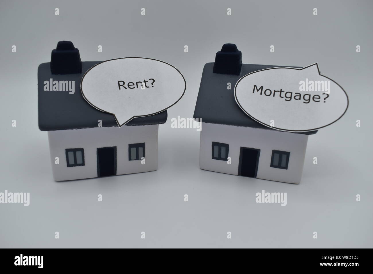 Two houses with speech boxes, one says 'Rent?', the other says 'Buy?'.  It's a dilemma facing the young and some older people. Stock Photo