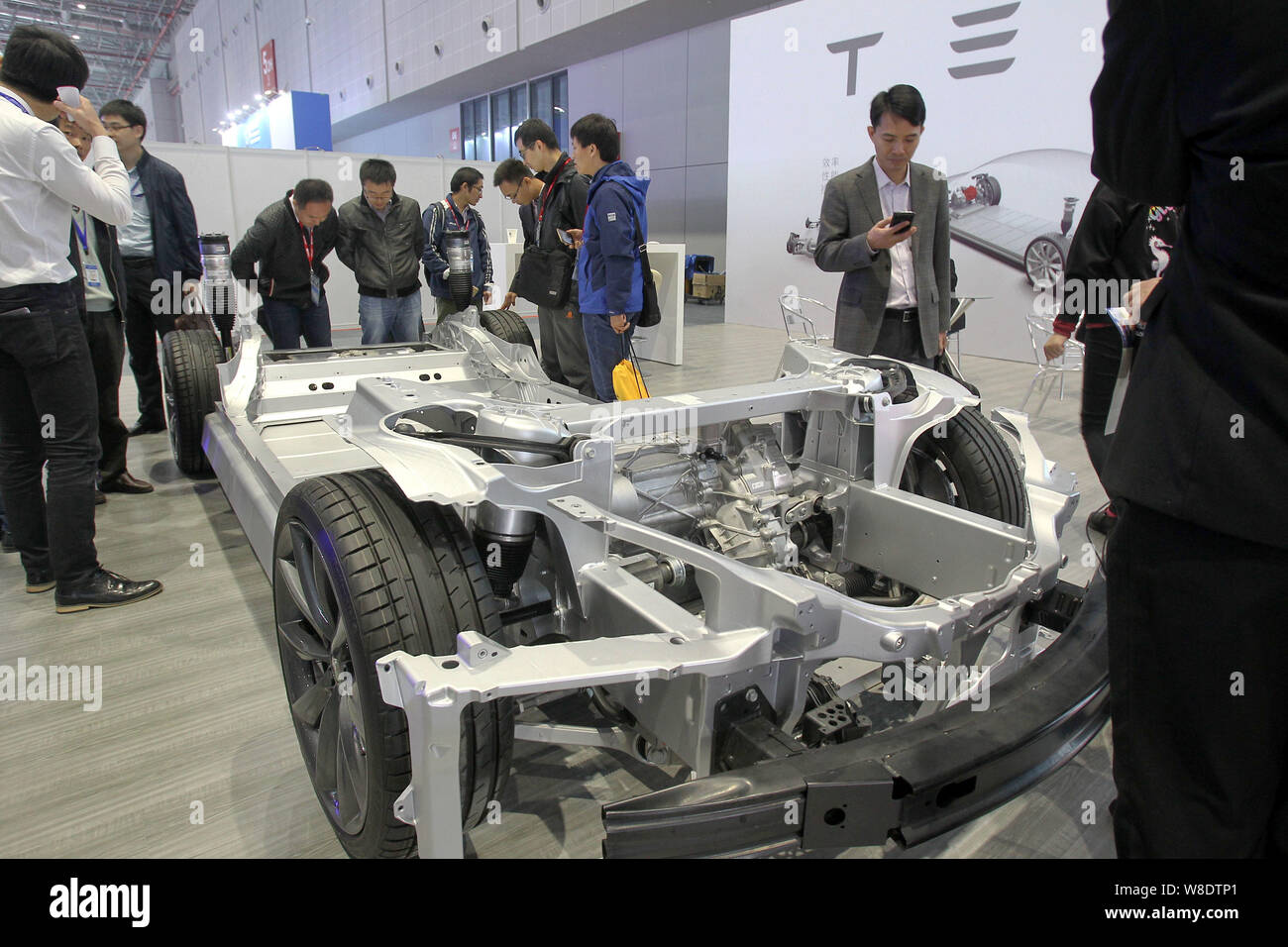 Visitors look at the chassis of a Tesla Model S electric car during the 17th China International Industry Fair in Shanghai, China, 3 November 2015. Stock Photo
