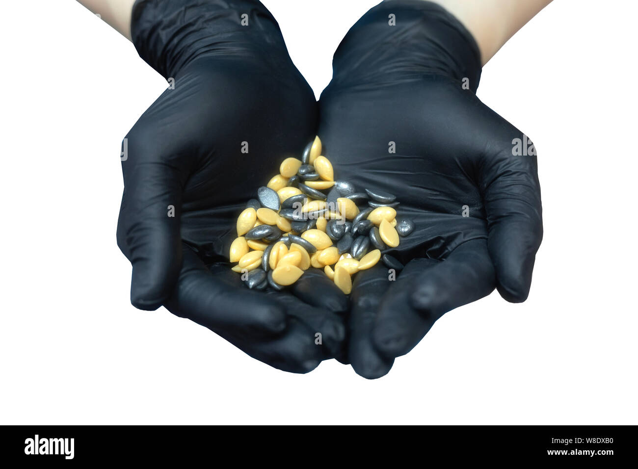 Girl cosmetician in black medical gloves with granules of wax for depilation in the shape of a heart on the palm Stock Photo