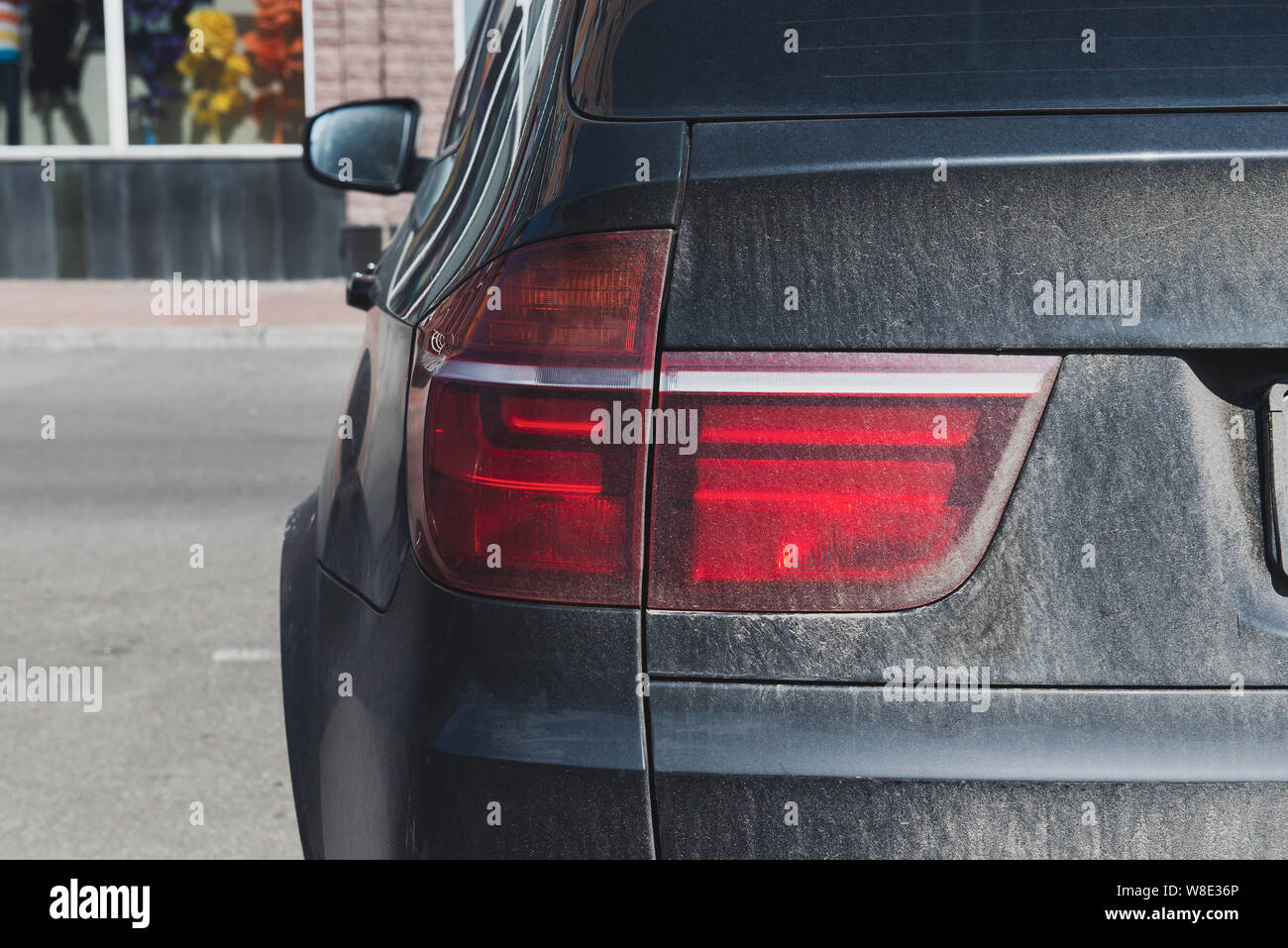 Back of a dirty black car. Dusty vehicle with backlight. Car is waiting
