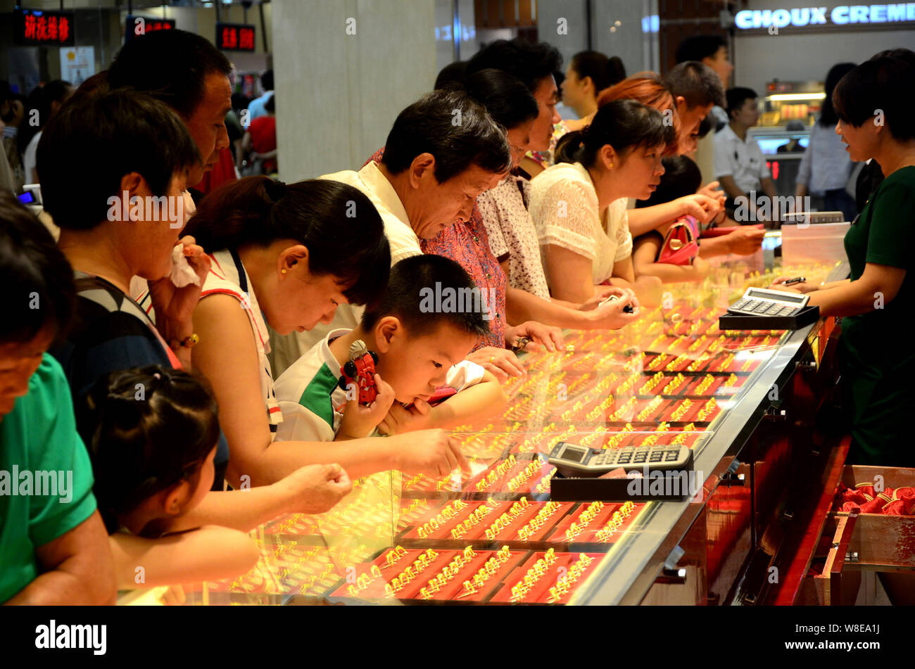 --FILE--Chinese customers buy gold ornaments at a jewelry store in Xuchang city, central China's Henan province, 12 August 2015.   Consumer sentiment Stock Photo