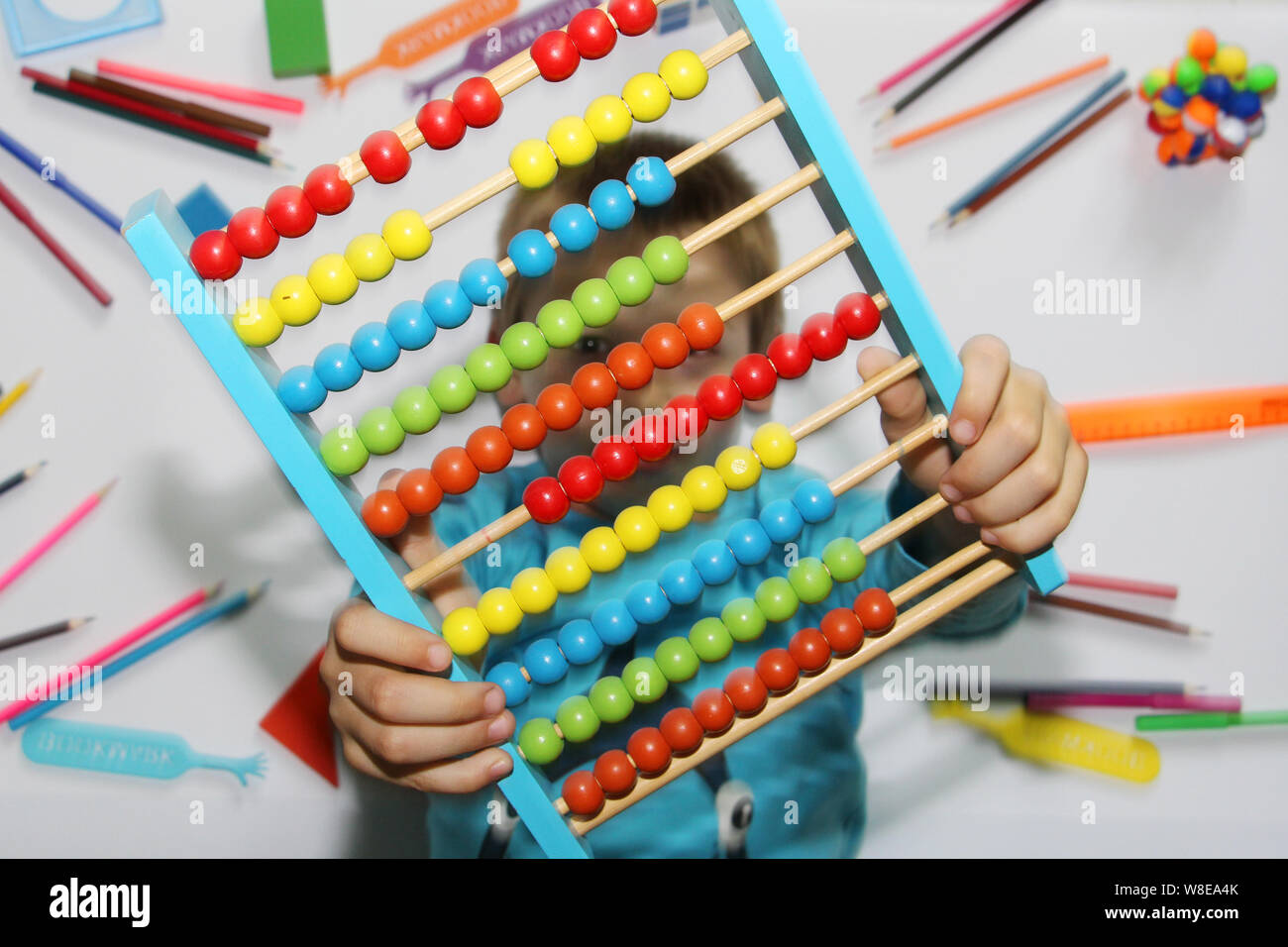 The boy holds big abacus in his hands. The abacus is colored, multi-colored in the hands of a child. The boy is getting ready to go to school. The chi Stock Photo