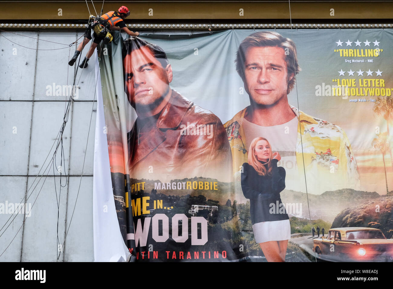 Haymarket, London, UK. 9th August 2019. Workmen installing a poster for the new Quentin Tarantino film Once Upon a Time In Hollywood. above the Empire cinema. Credit: Matthew Chattle/Alamy Live News Stock Photo