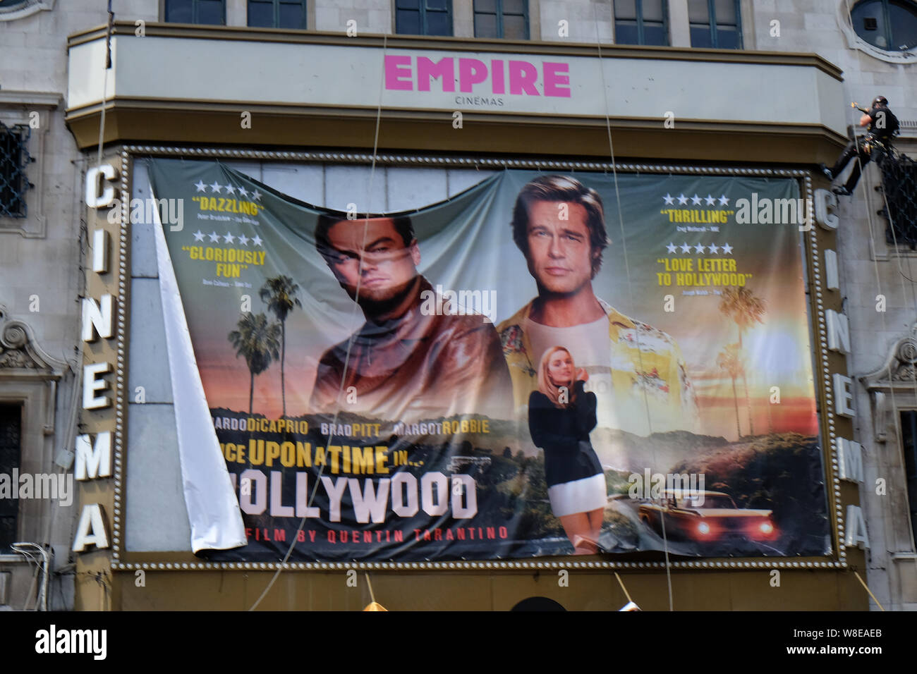 Haymarket, London, UK. 9th August 2019. Workmen installing a poster for the new Quentin Tarantino film Once Upon a Time In Hollywood. above the Empire cinema. Credit: Matthew Chattle/Alamy Live News Stock Photo