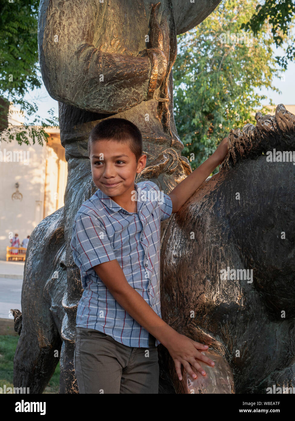 Boy at statue of Nasreddin, Historic City of Bukhara, Uzbekistan, Asia Stock Photo