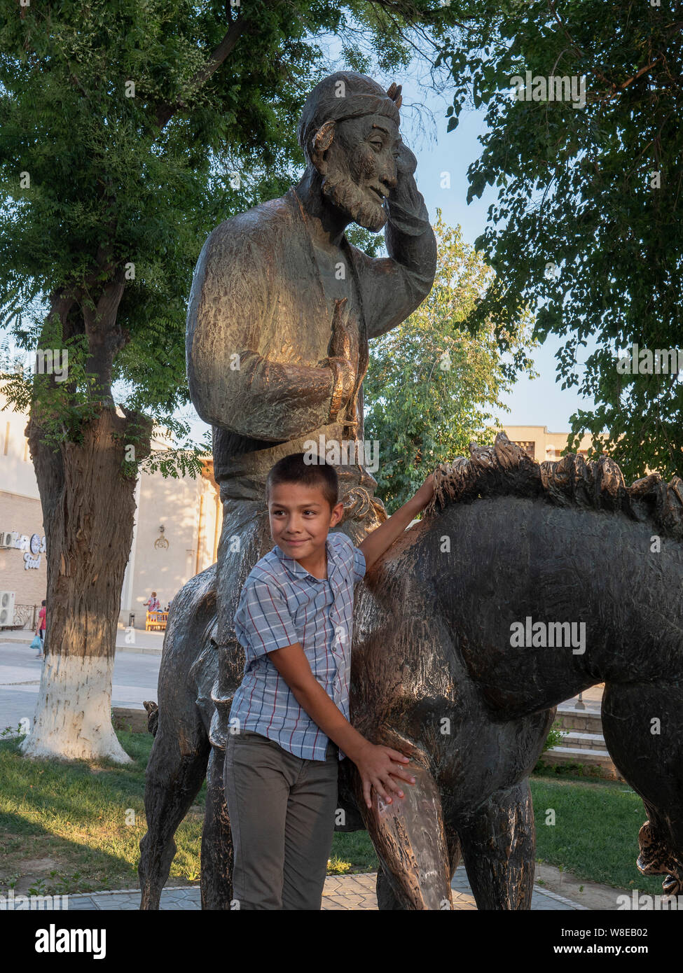 Boy at statue of Nasreddin, Historic City of Bukhara, Uzbekistan, Asia Stock Photo