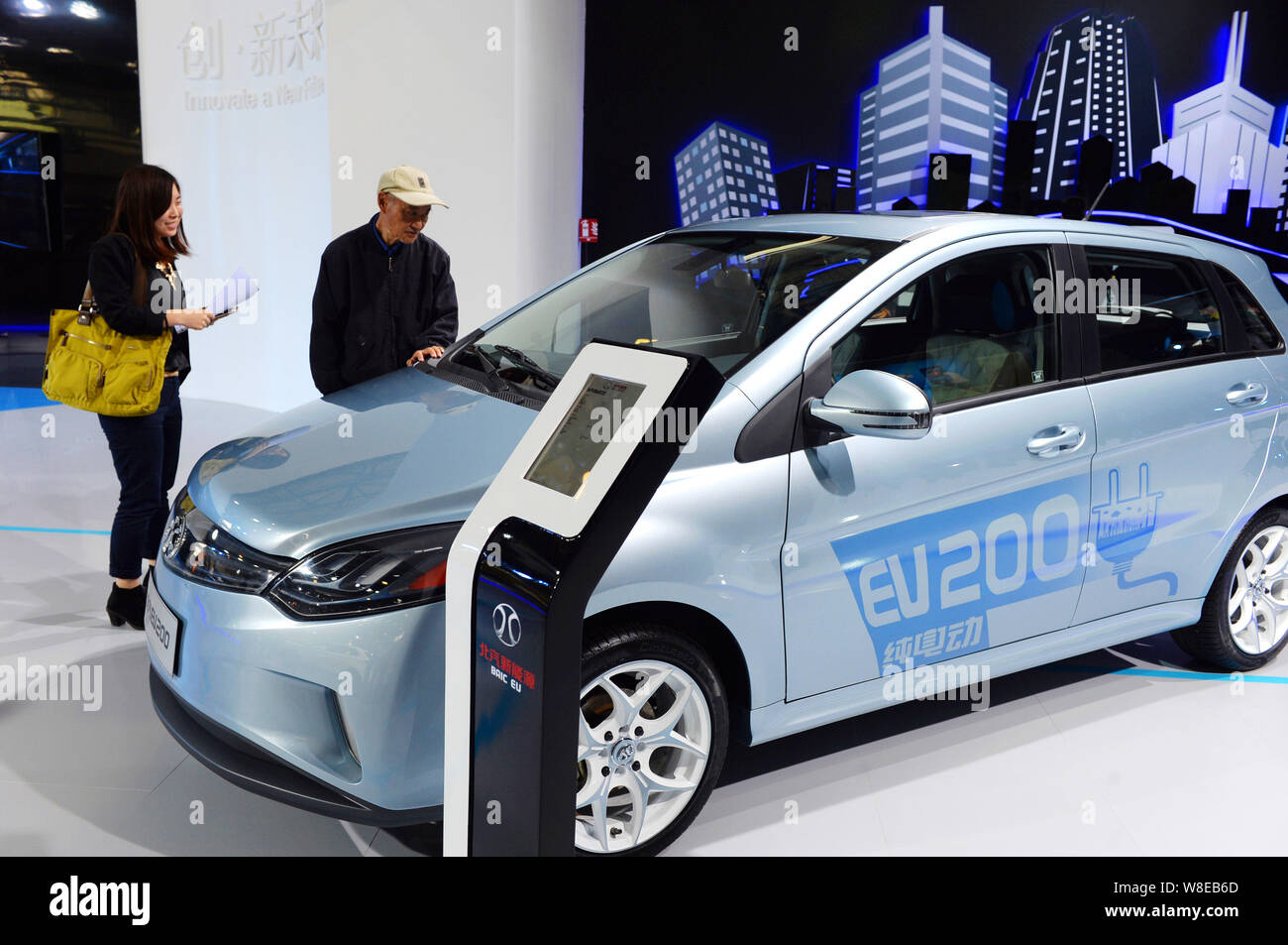 --FILE--Visitors look at an EV200 electric car of BAIC during an expo in Beijing, China, 13 May 2015.  China will soon approve production licenses for Stock Photo