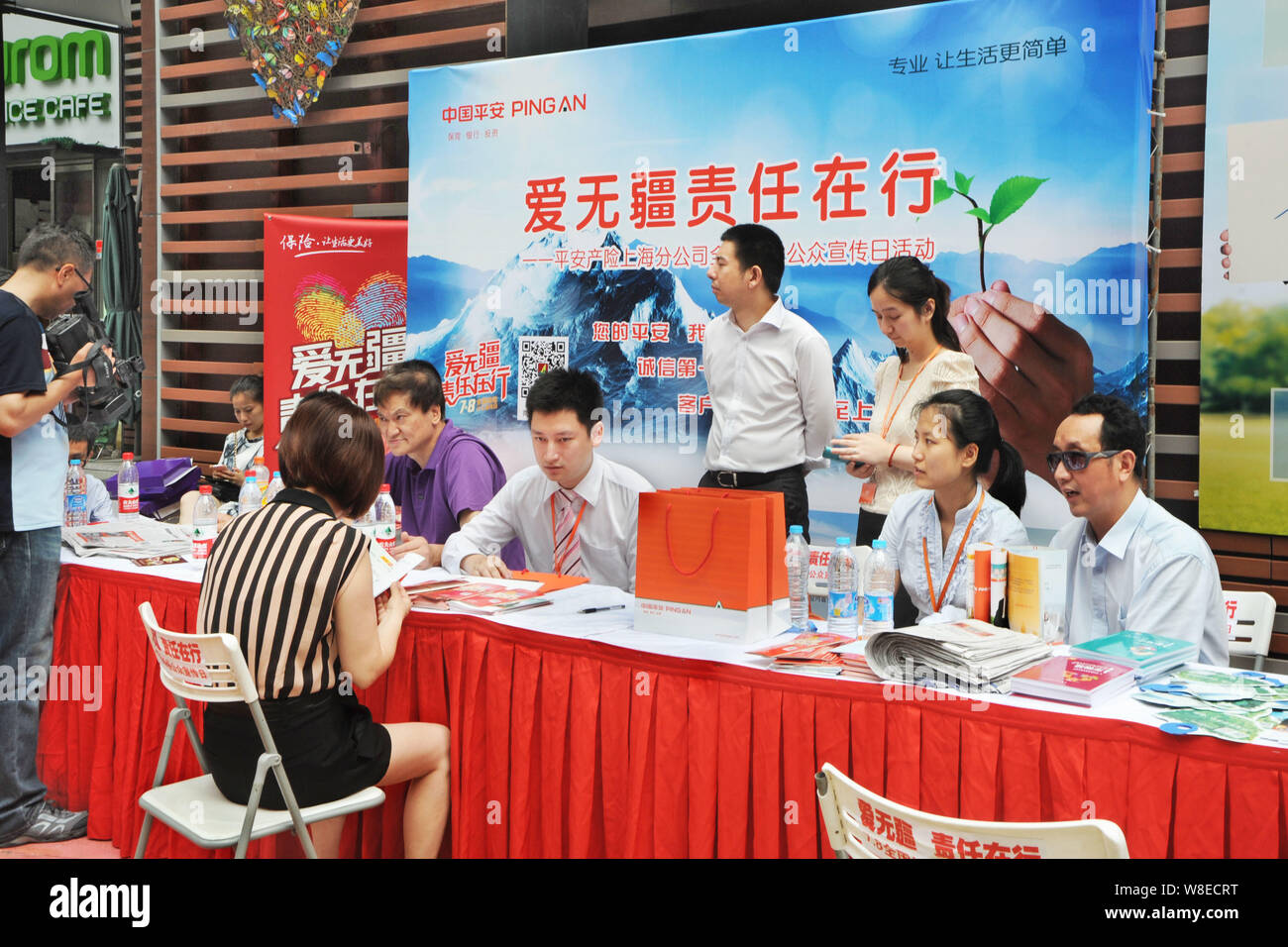 File A Chinese Employee Deals With A Visitor At The Stand Of Ping An Insurance Group Company Of China During A Promotional Event In Shanghai Chi Stock Photo Alamy