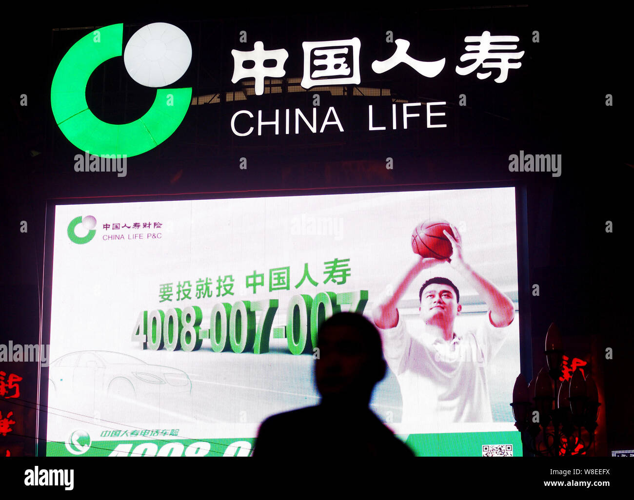 --FILE--A pedestrian walks past an advertisement of China Life Insurance (Group) Company in Beijing, China, 27 October 2013.  Chinese insurers are on Stock Photo