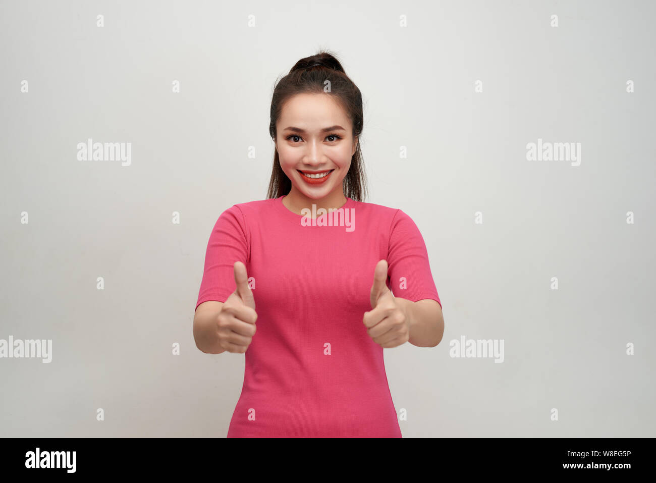 Enthusiastic motivated attractive young woman giving a thumbs up gesture of approval and success with a beaming smile Stock Photo