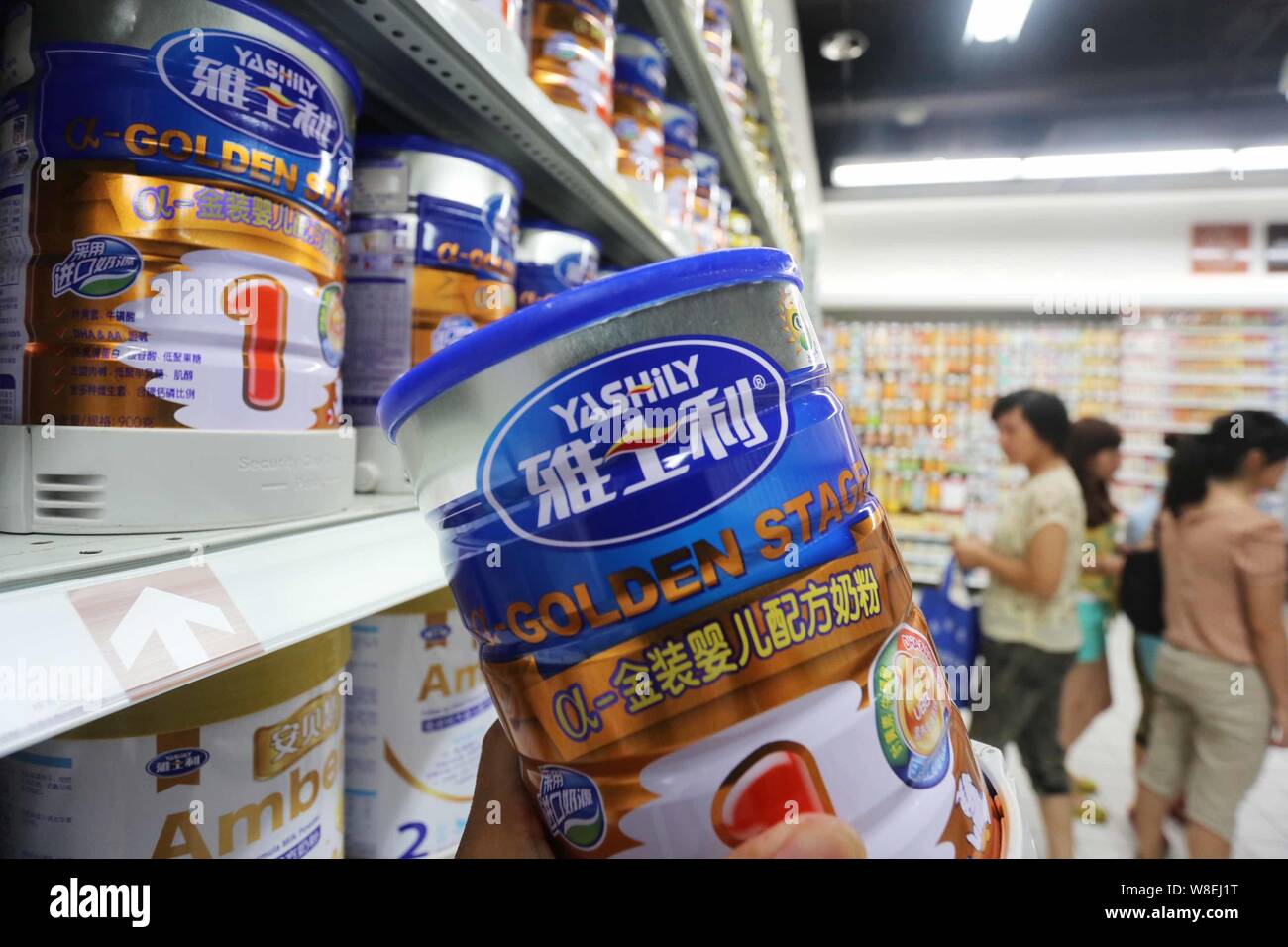 --FILE--A customer shops for a tin of Yashily infant milk formula at a supermarket in Xuchang city, central China's Henan province, 8 August 2013. Stock Photo