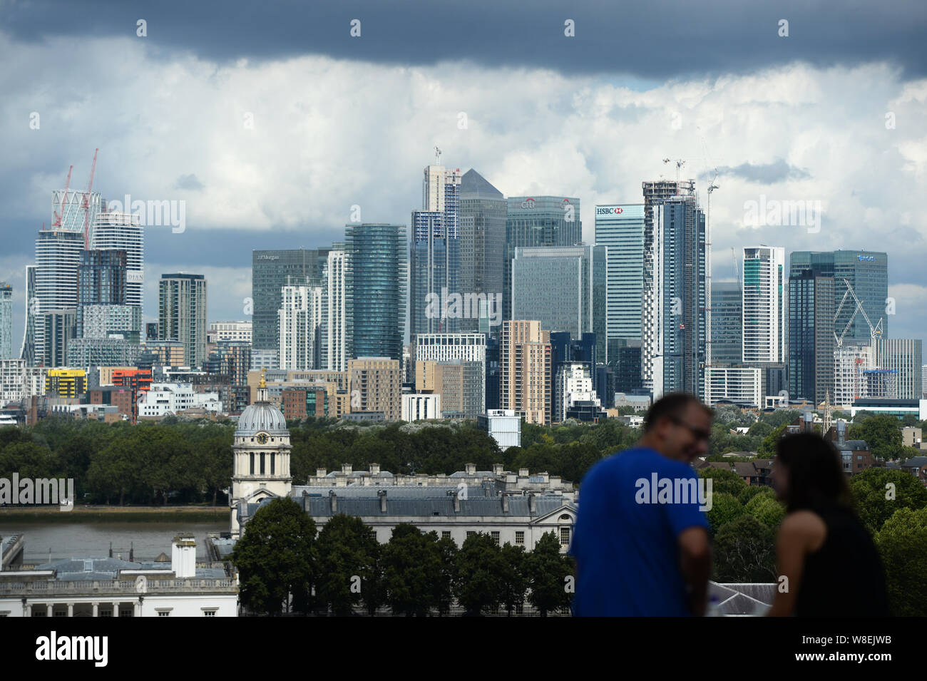 People observe the view of the Old Royal Naval College and Canary Wharf, from the Royal Observatory in Greenwich, London. Warnings for rain and wind came into force across nearly all of the UK today. Stock Photo