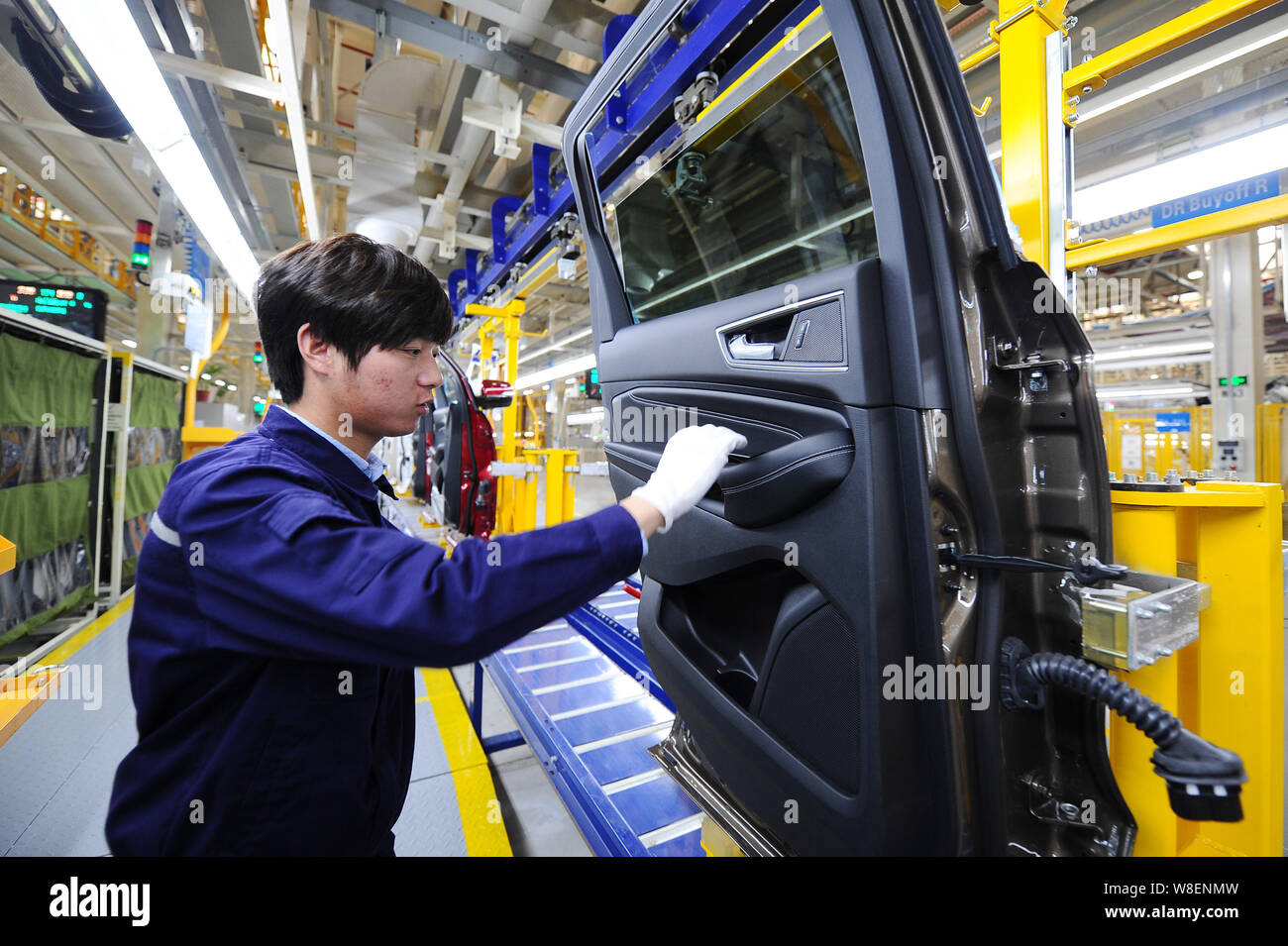 A Chinese worker checks a door of a Ford SUV on the assembly line at ...