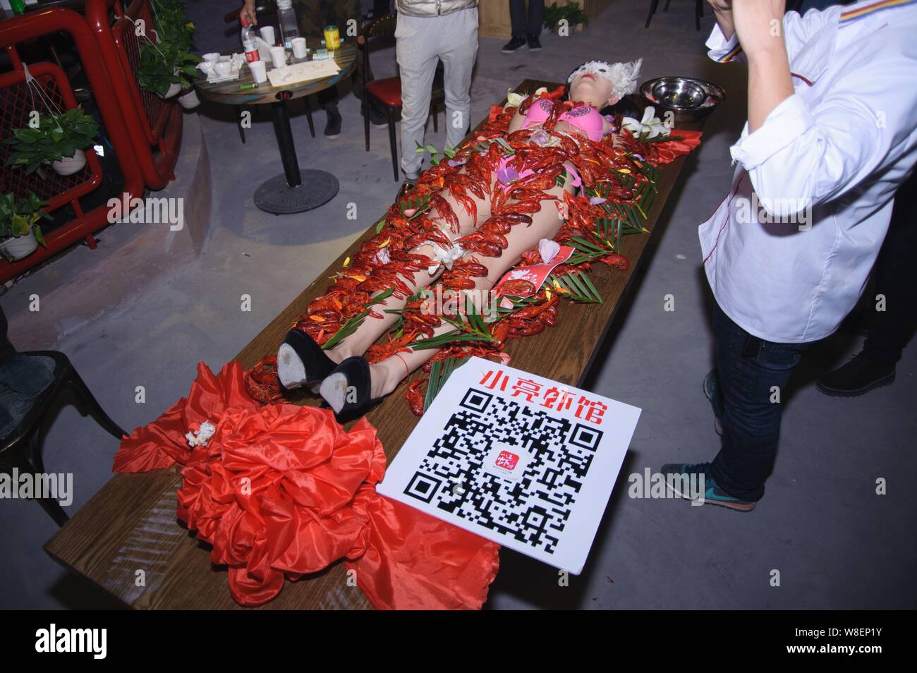 View of a bikinidressed model lying on a table with crayfish sprawled