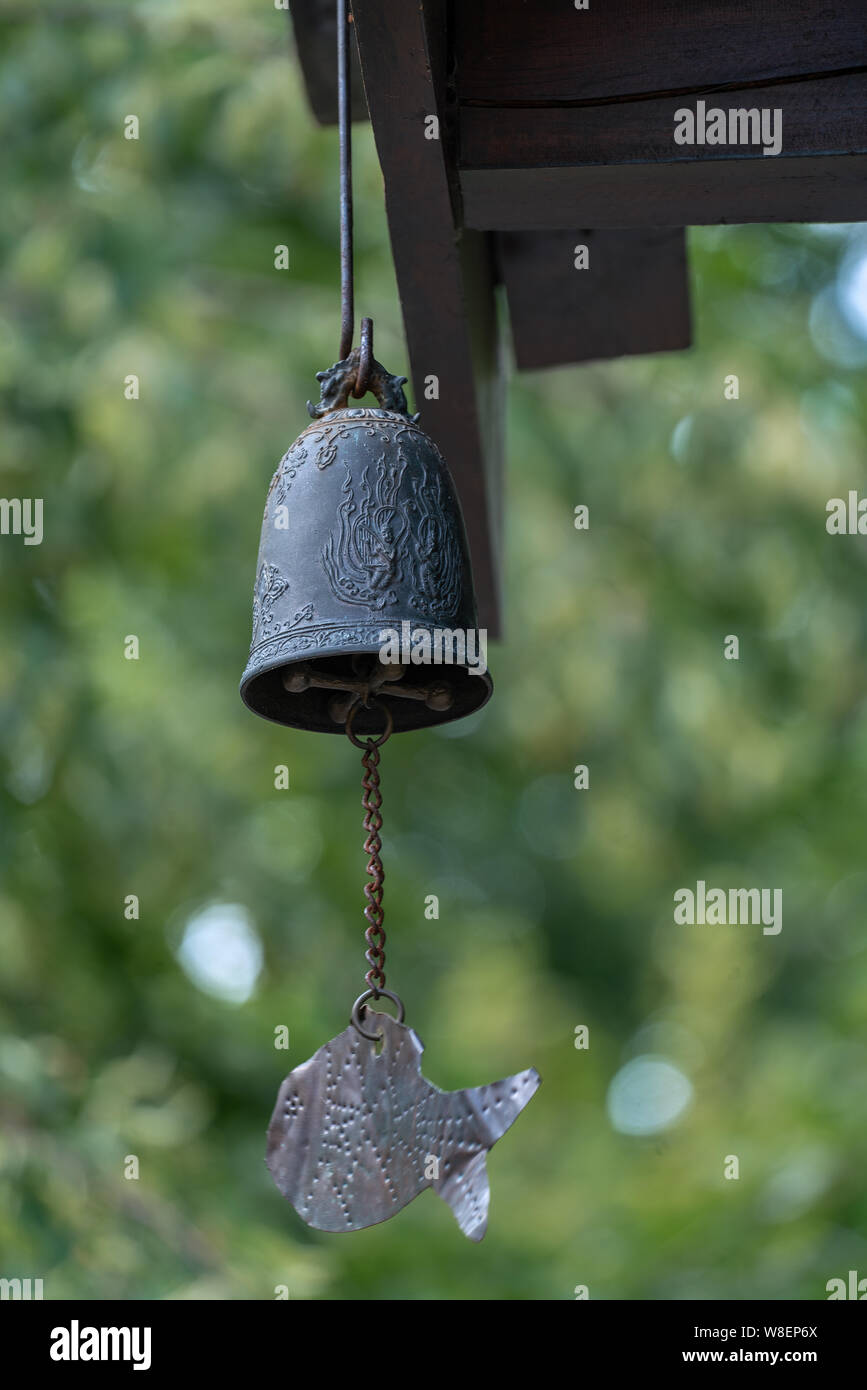 Asian windchime made of a metal bell and a lucky fish decorated with hindu gods Stock Photo