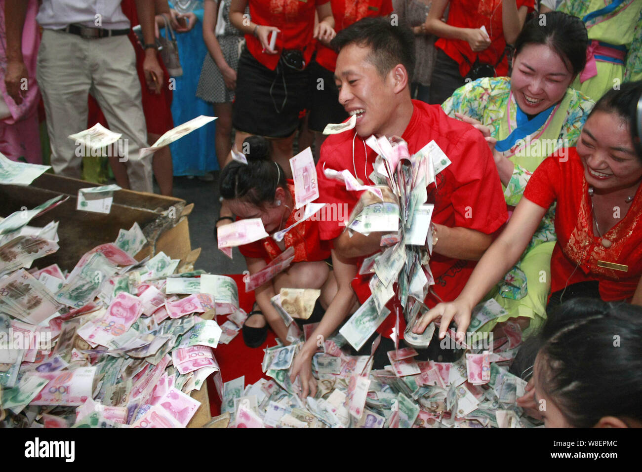 Chinese performers collect the money paid by tourists after a performance as the banknotes are dumpped by a bulldozer at "The City of Song" scenic spo Stock Photo