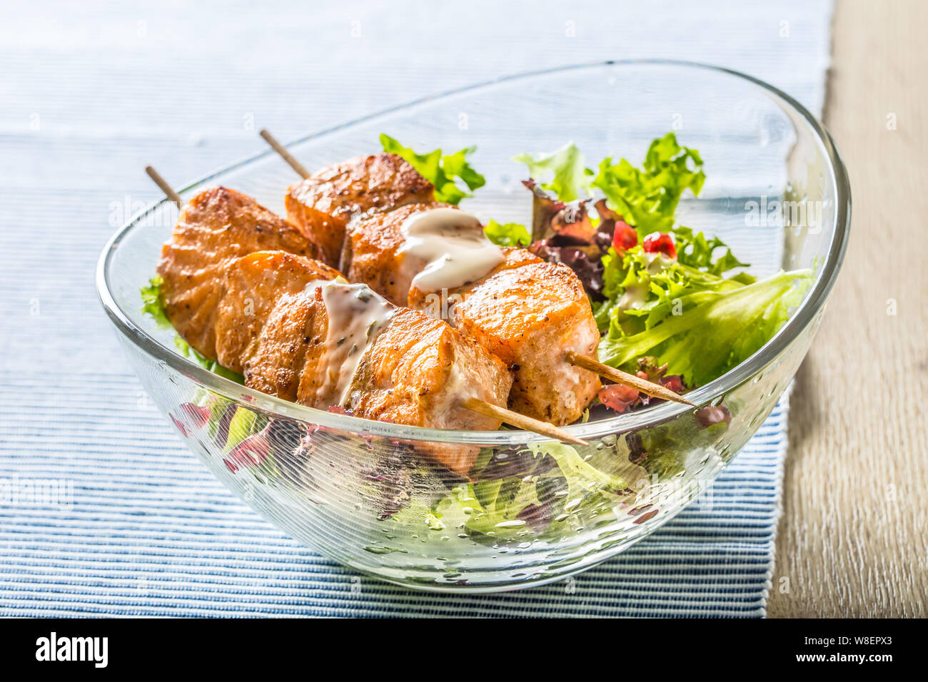 Grilled salmon skewers with summer lettuce salat pomehranate seeds olive oil and dressing. Healthy fish food with fruit and vegetable Stock Photo