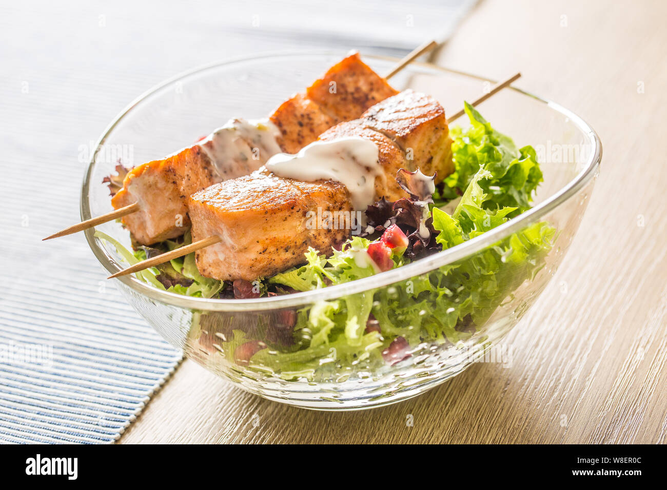 Grilled salmon skewers with summer lettuce salat pomehranate seeds olive oil and dressing. Healthy fish food with fruit and vegetable Stock Photo