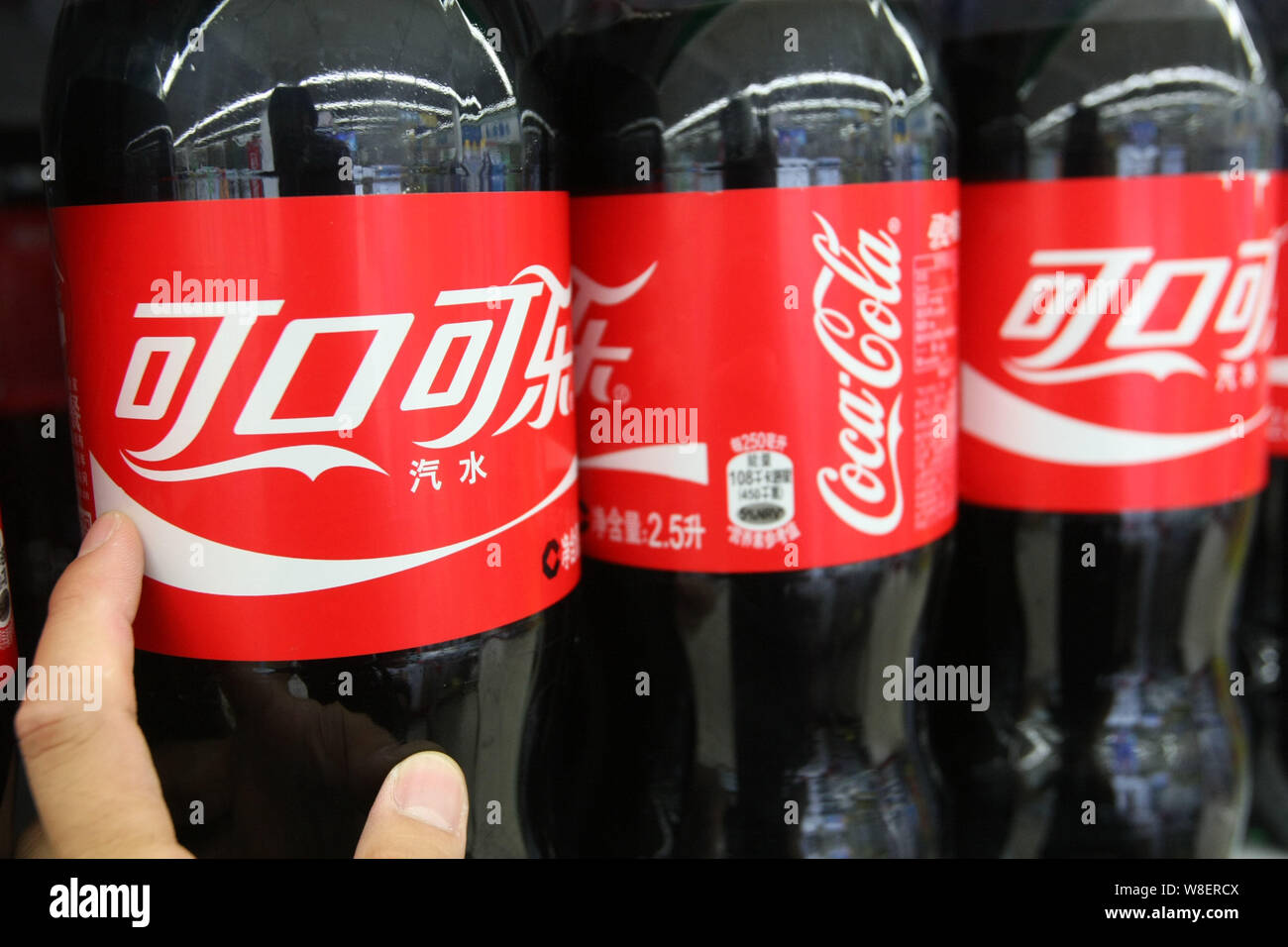 --FILE--A customer shops for a bottle of Coca-Cola at a supermarket in Shanghai, China, 16 July 2014.   Coca-Cola has pointed to further signs that it Stock Photo