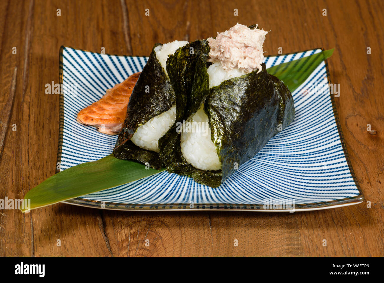 onigiri of roasted tuna and salmon, wrapped in seaweed, darl wood table ...