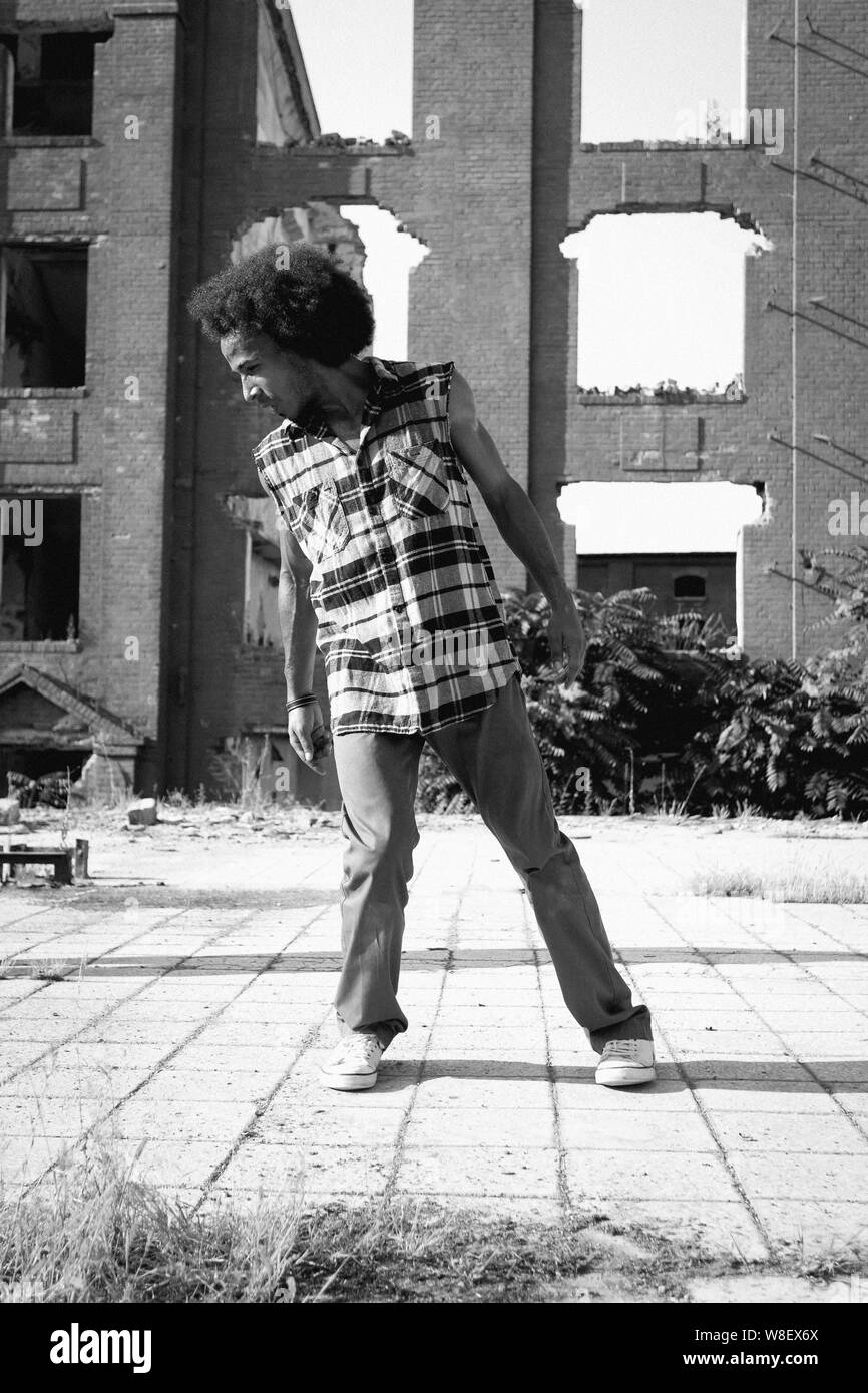 Young African American man hip hop dancing in an urban square, lit by a ...