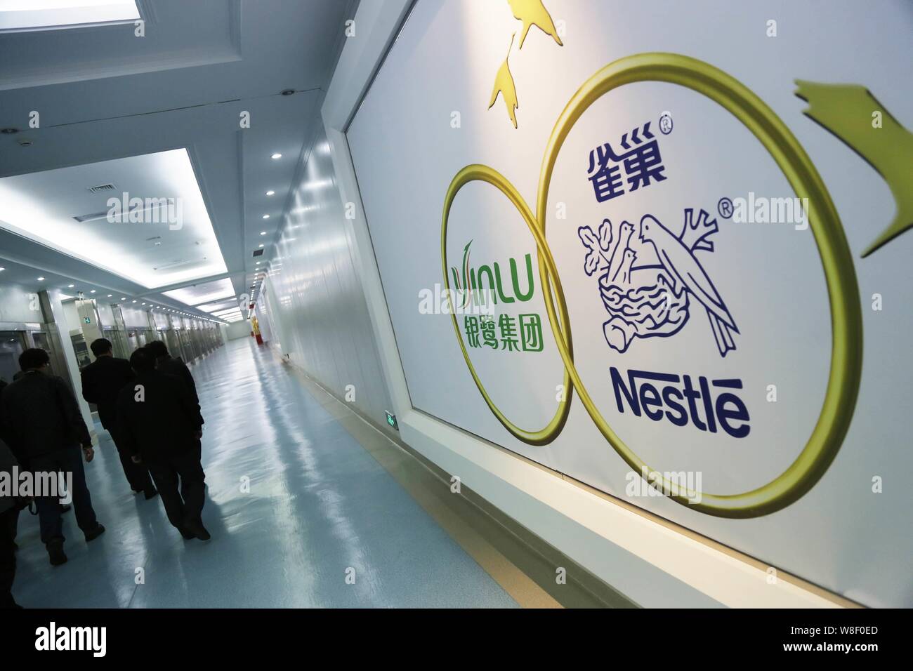 --FILE--Visitors walk past logos of Nestle and Yinlu at the office building of their joint venture in Chuzhou city, east China's Anhui province, 6 Dec Stock Photo
