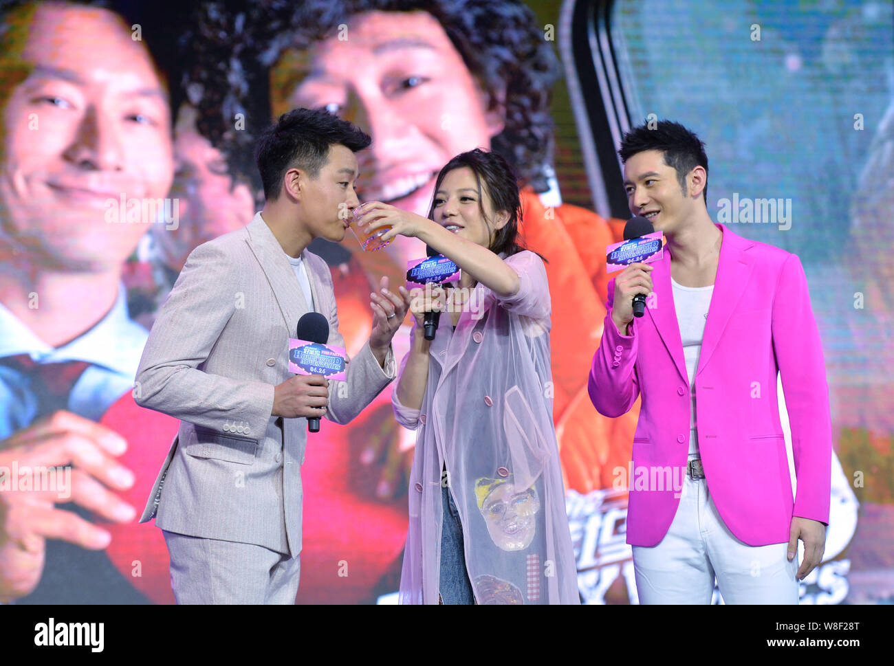 Chinese actress Vicki Zhao Wei, center, feeds actor Tong Dawei, left, juice next to actor Huang Xiaoming during the premiere of their new movie 'Holly Stock Photo