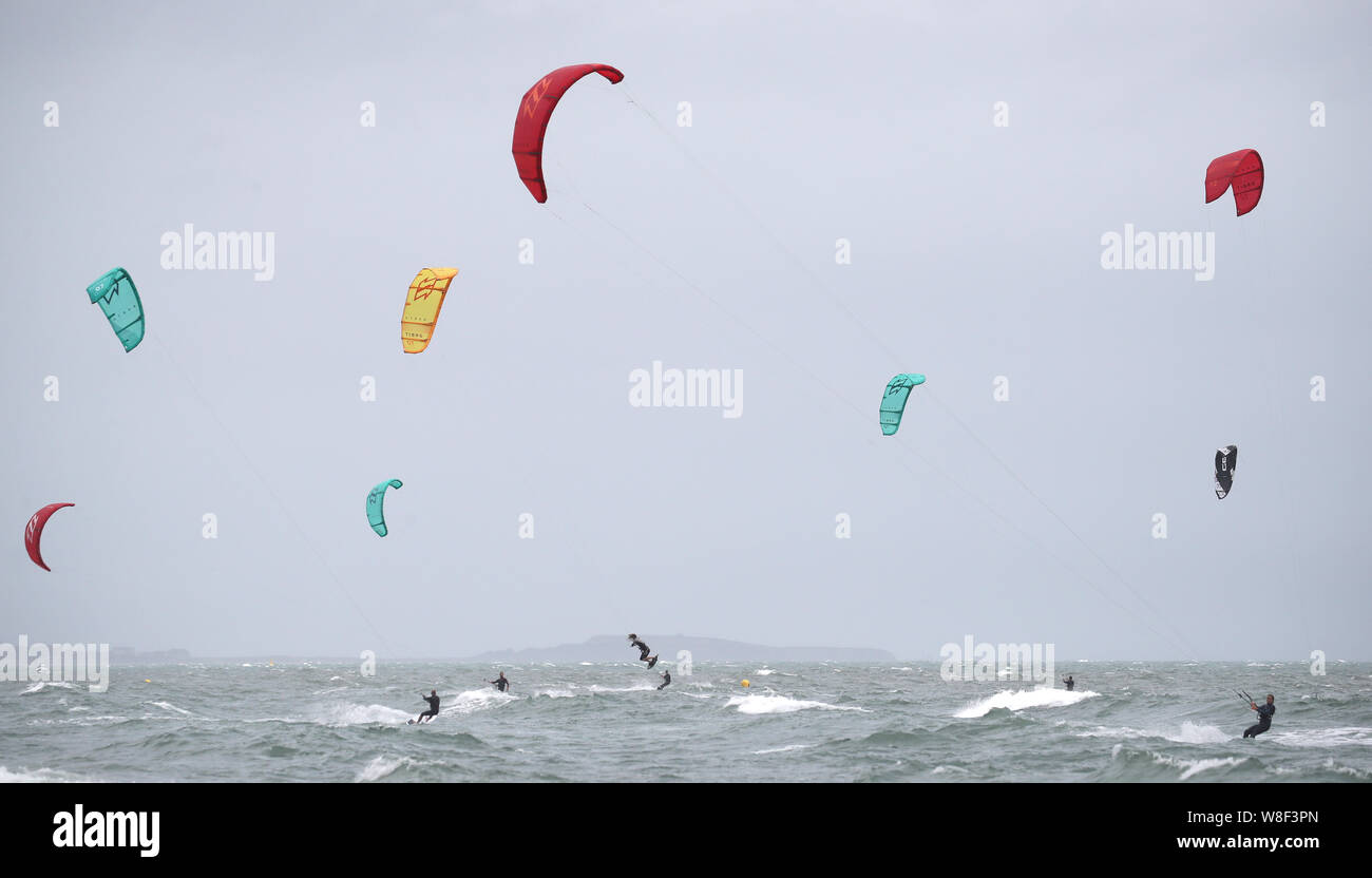 Kite surfers enjoy the strong winds off of Branksome Chine, near Poole in Dorset. Warnings for rain and wind came into force across nearly all of the UK today. Stock Photo