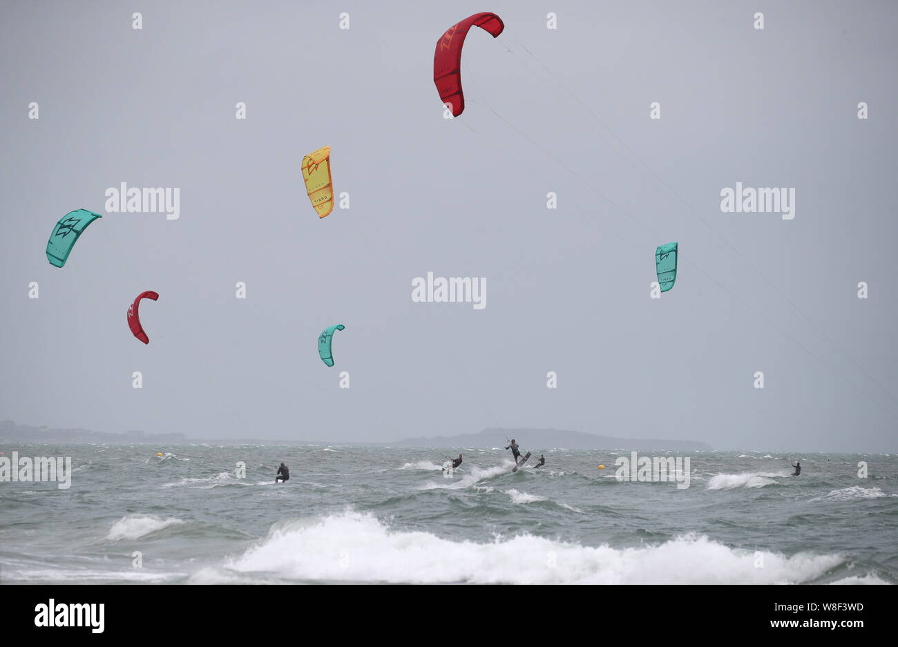 Kite surfers enjoy the strong winds off of Branksome Chine, near Poole in Dorset. Warnings for rain and wind came into force across nearly all of the UK today. Stock Photo