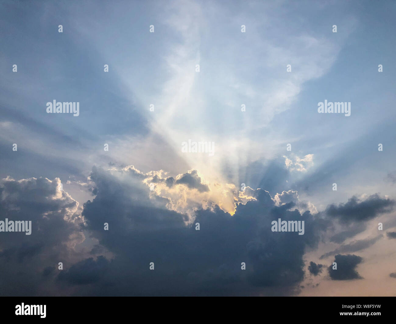 Rays of sunlight through dark clouds at sunset Stock Photo