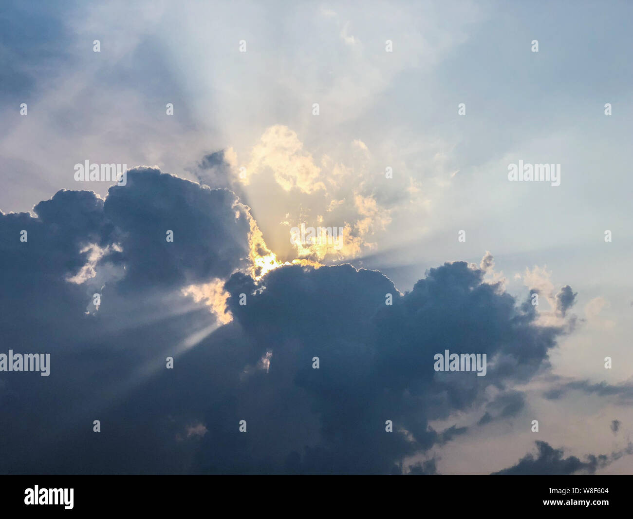 Rays of sunlight through dark clouds at sunset Stock Photo