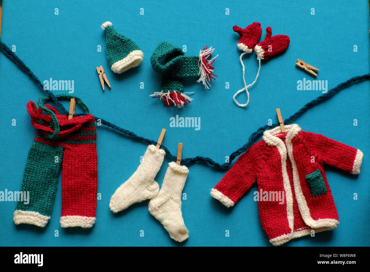 Top view of Santa clothes with accessories as gloves, hat, scarf, socks in white, red and green knit from yarn on blue background, small decorations Stock Photo